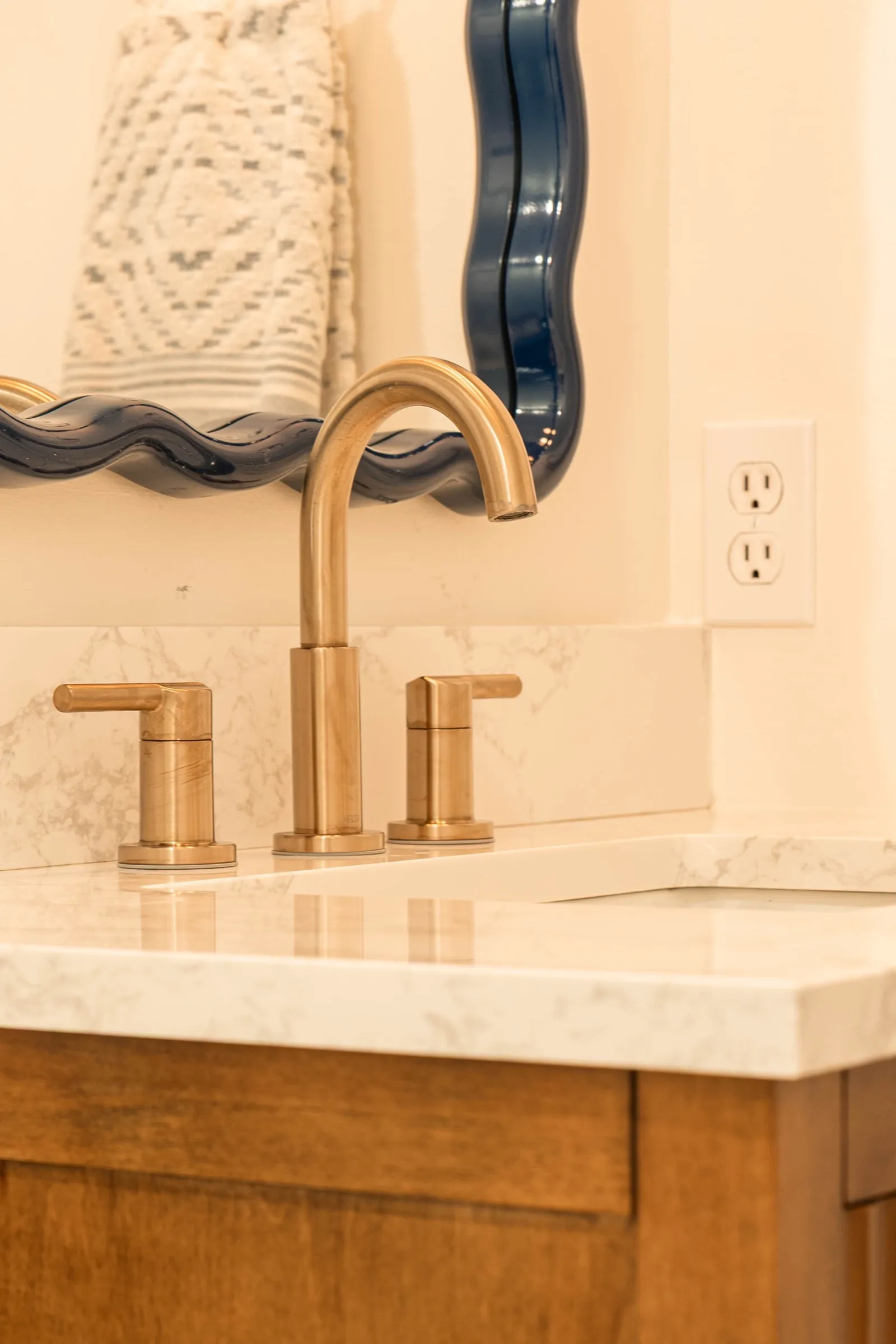 Brass widespread tap set into the marble counter of the walnut vanity