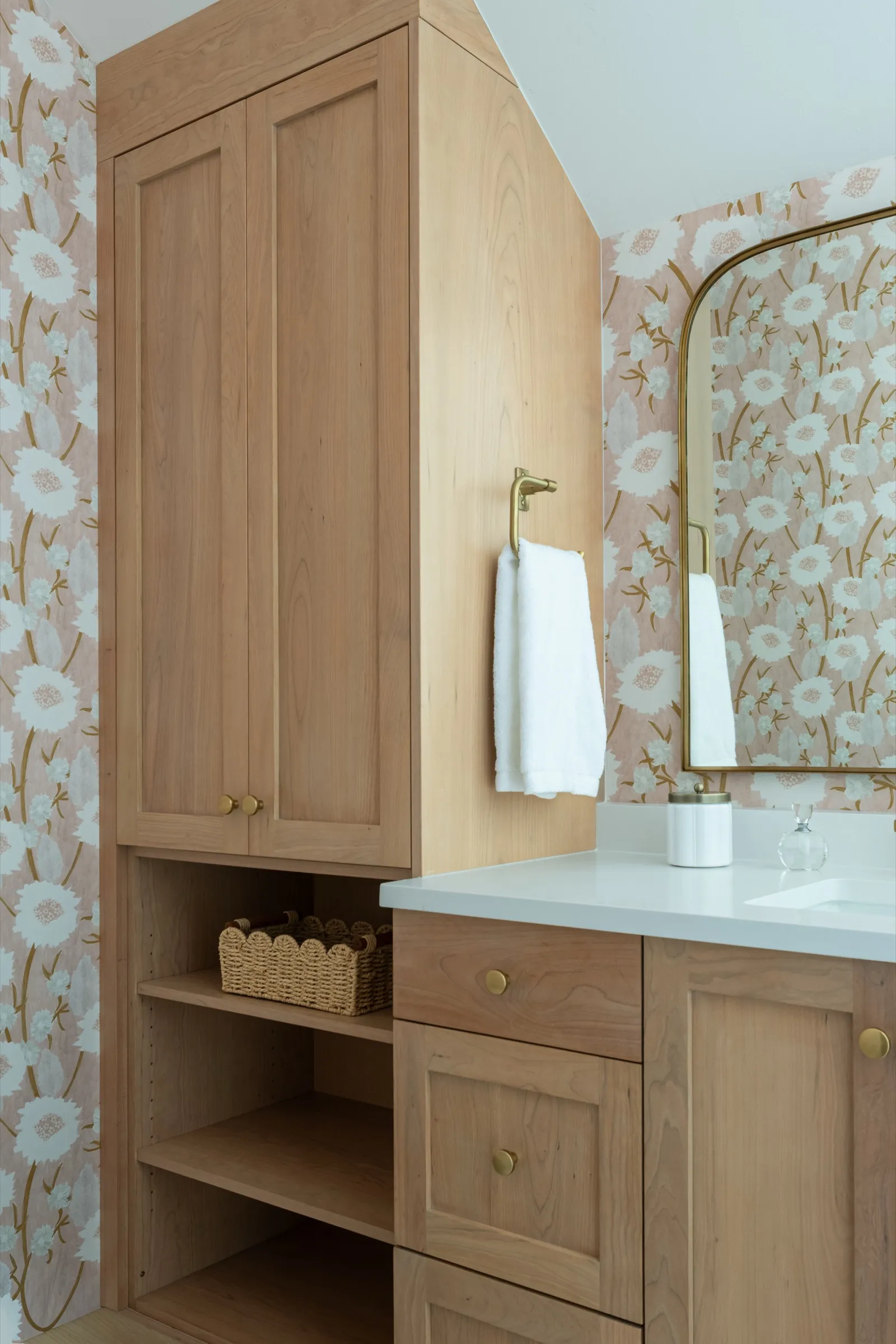Tall white oak cabinet with open shelves and a woven basket beside the vanity