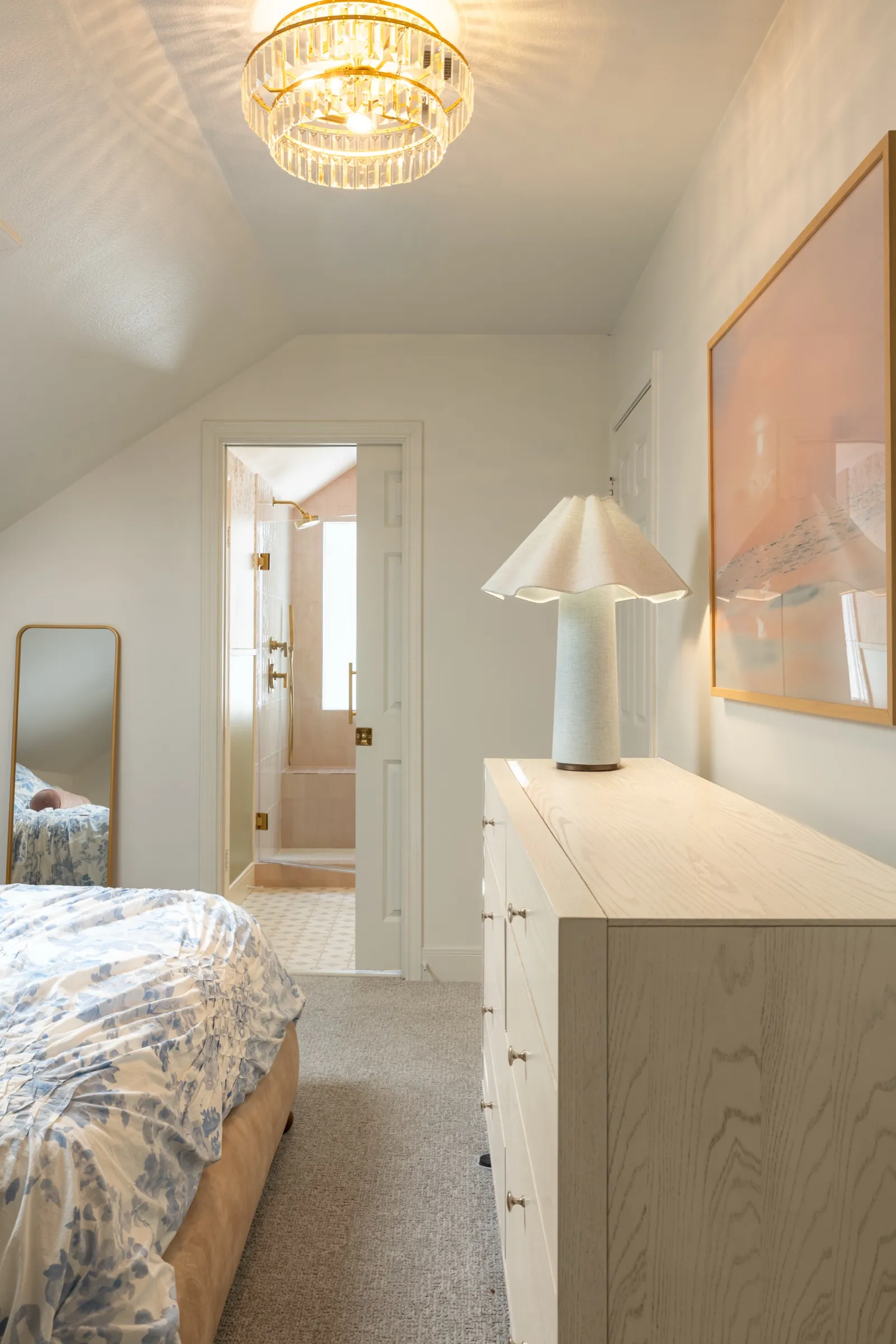 Bedroom under a sloping ceiling with a glass flush light, a pale oak dresser and a view through to the pink bathroom