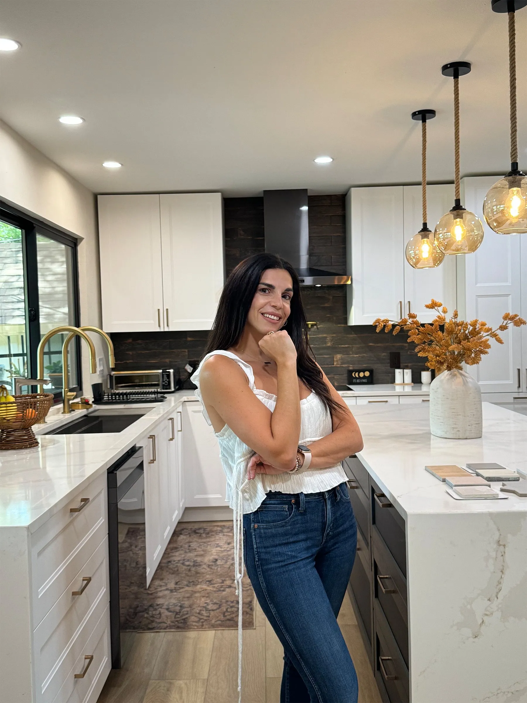 Yara Khuri standing at the island of a kitchen she designed, tile samples laid out on the counter beside her